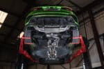 Scorpion RVS Sportuitlaat - Audi RS3 8Y Sportsback (OPF) - Met klep - Resonated uivoering met Carbon Fiber ovale uitlaatsierstukken - gemonteerd op een groene RS3 8Y die op een werkplaatsbrug staat